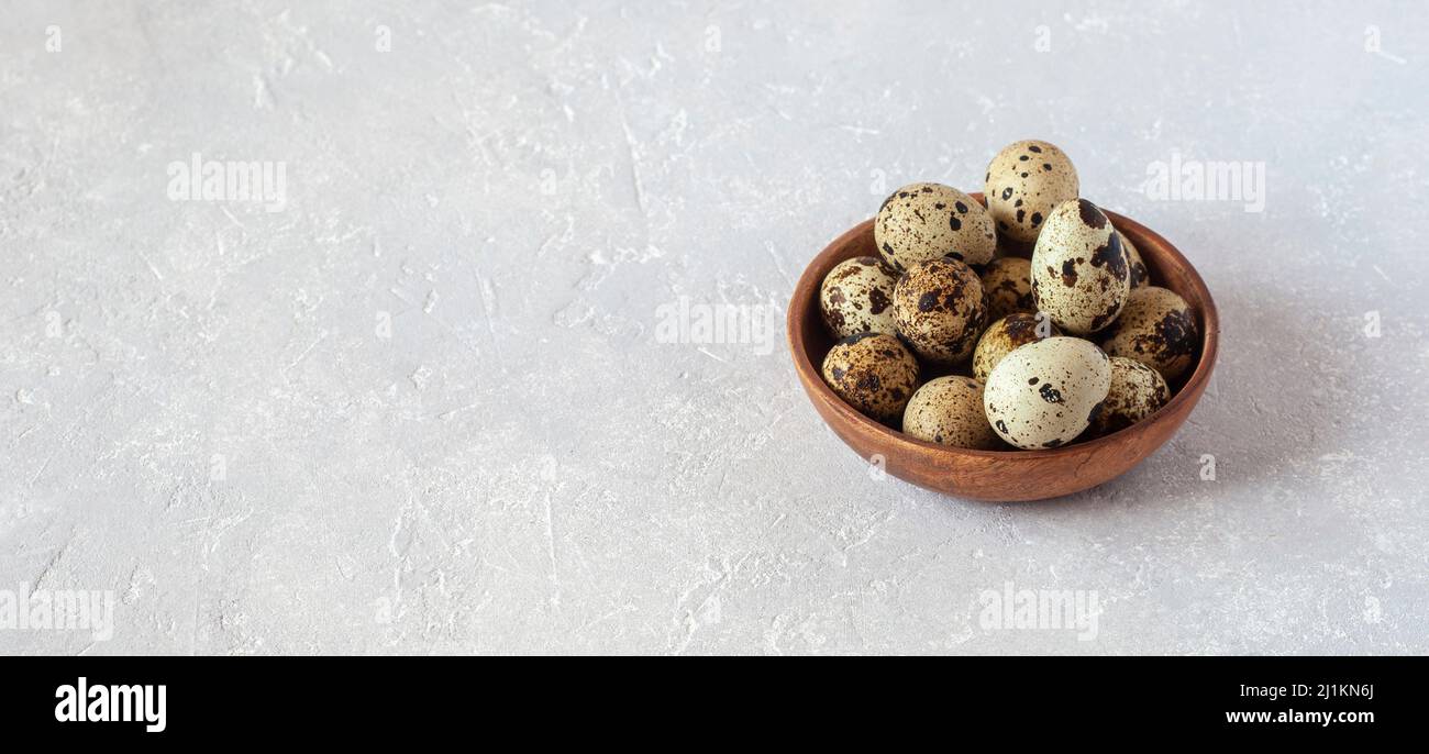 Œufs de caille dans un bol en bois sur fond de béton gris, espace de copie, minimalisme, concept de Pâques Banque D'Images
