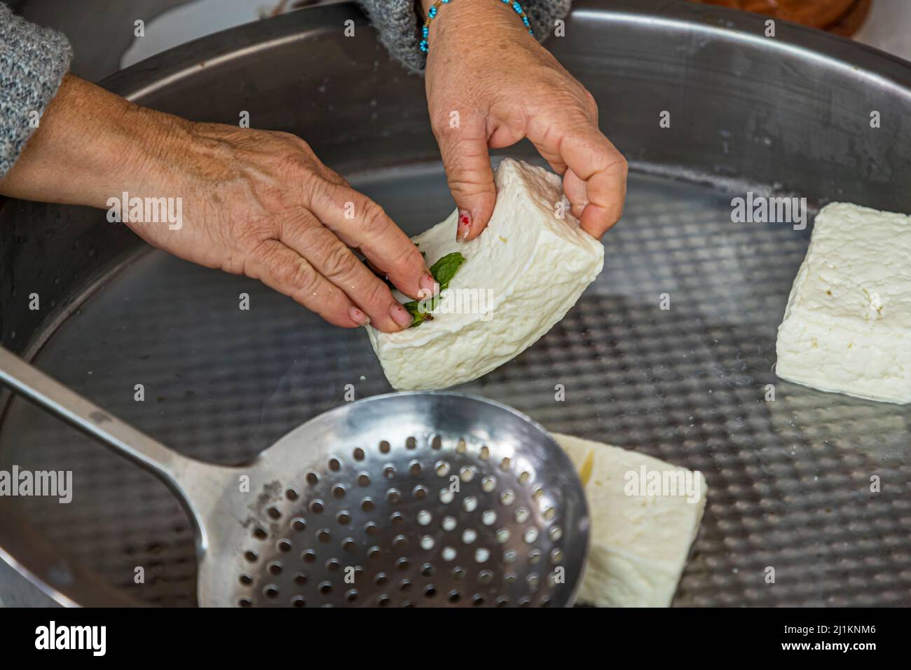 Dans le village d'Akdeniz, qui traduit signifie mer Méditerranée, vous obtenez une impression de la vie typique de pays chypriote. Chaque jour, la fromagère Fatma Haloumi (Hellim), la spécialité chypriote la plus célèbre à base de lait de chèvre et de lait de brebis. Les morceaux Hellim cuits et salés sont frottés à la menthe fraîche. Préparation de la spécialité au fromage Hellim ou Halloumi à Akdemiz, Chypre du Nord Banque D'Images