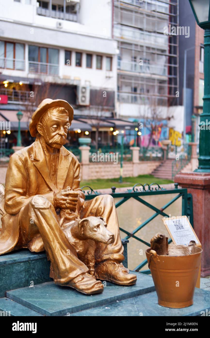Statue en bronze d'un vieil homme assis avec un chien et un poisson dans un seau au bord de la rivière Banque D'Images