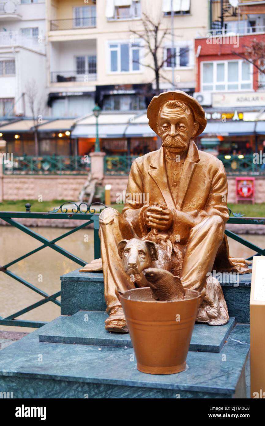 Statue en bronze d'un vieil homme assis avec un chien et un poisson dans un seau au bord de la rivière Banque D'Images