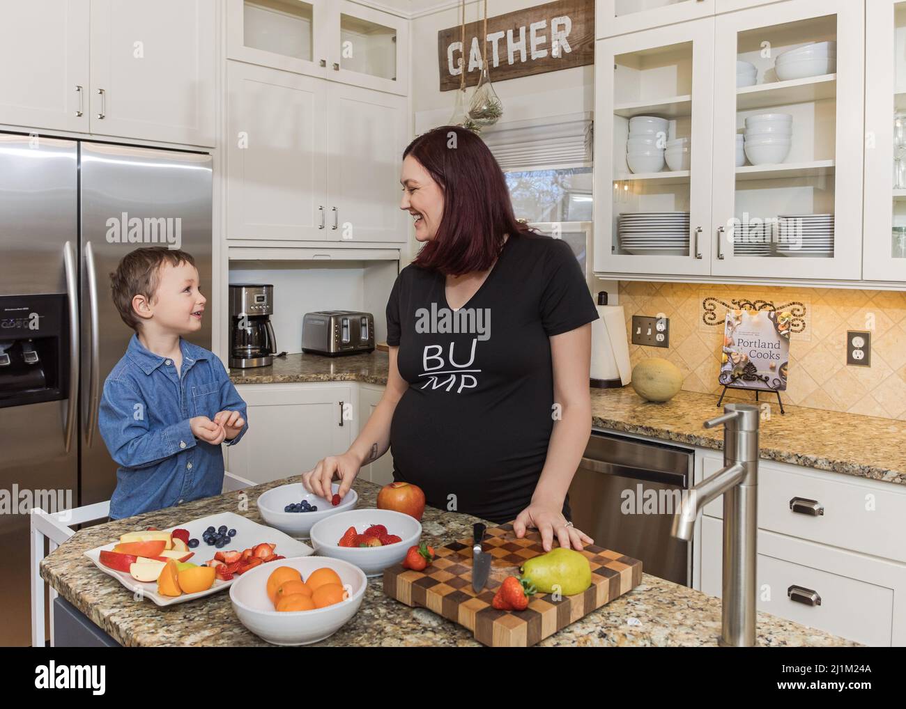 Maman enceinte et son tout-petit qui se réunissent dans la cuisine pour préparer des collations santé Banque D'Images