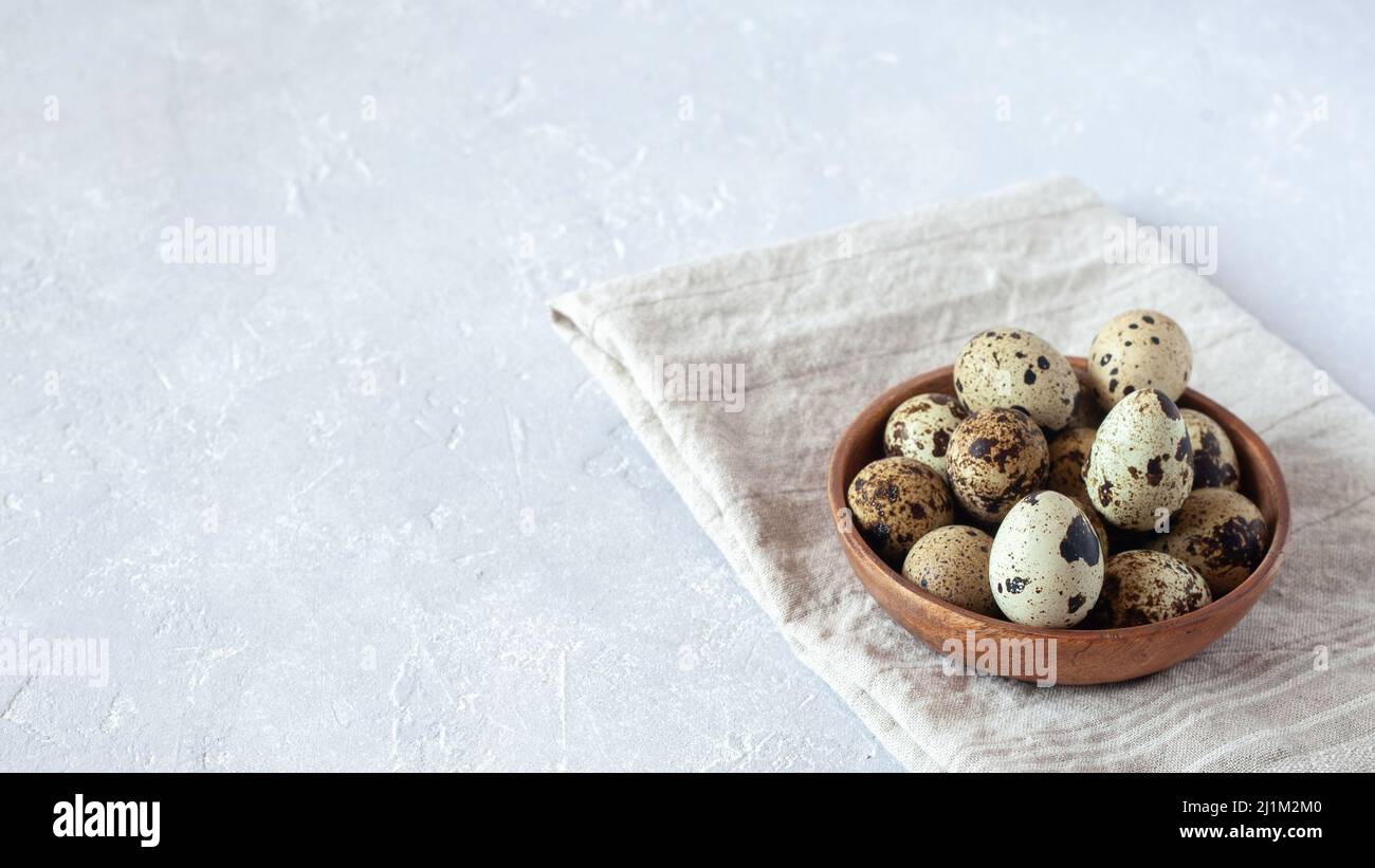 petit bol en bois d'œufs de caille sur tissu beige, fond en béton gris, espace de copie Banque D'Images