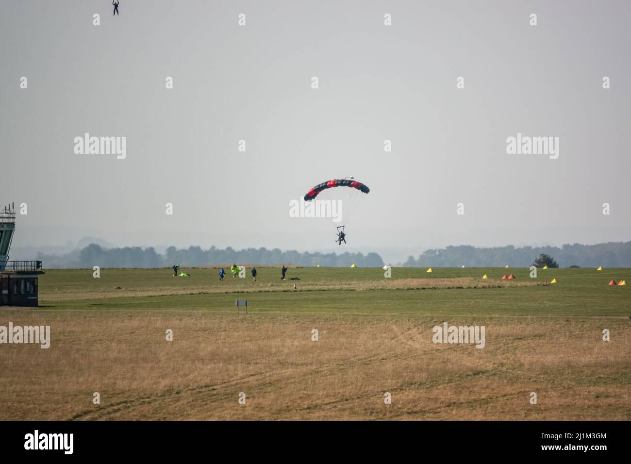 Saut en parachute arrivant sur un terrain d'aviation en herbe, ciel bleu Banque D'Images