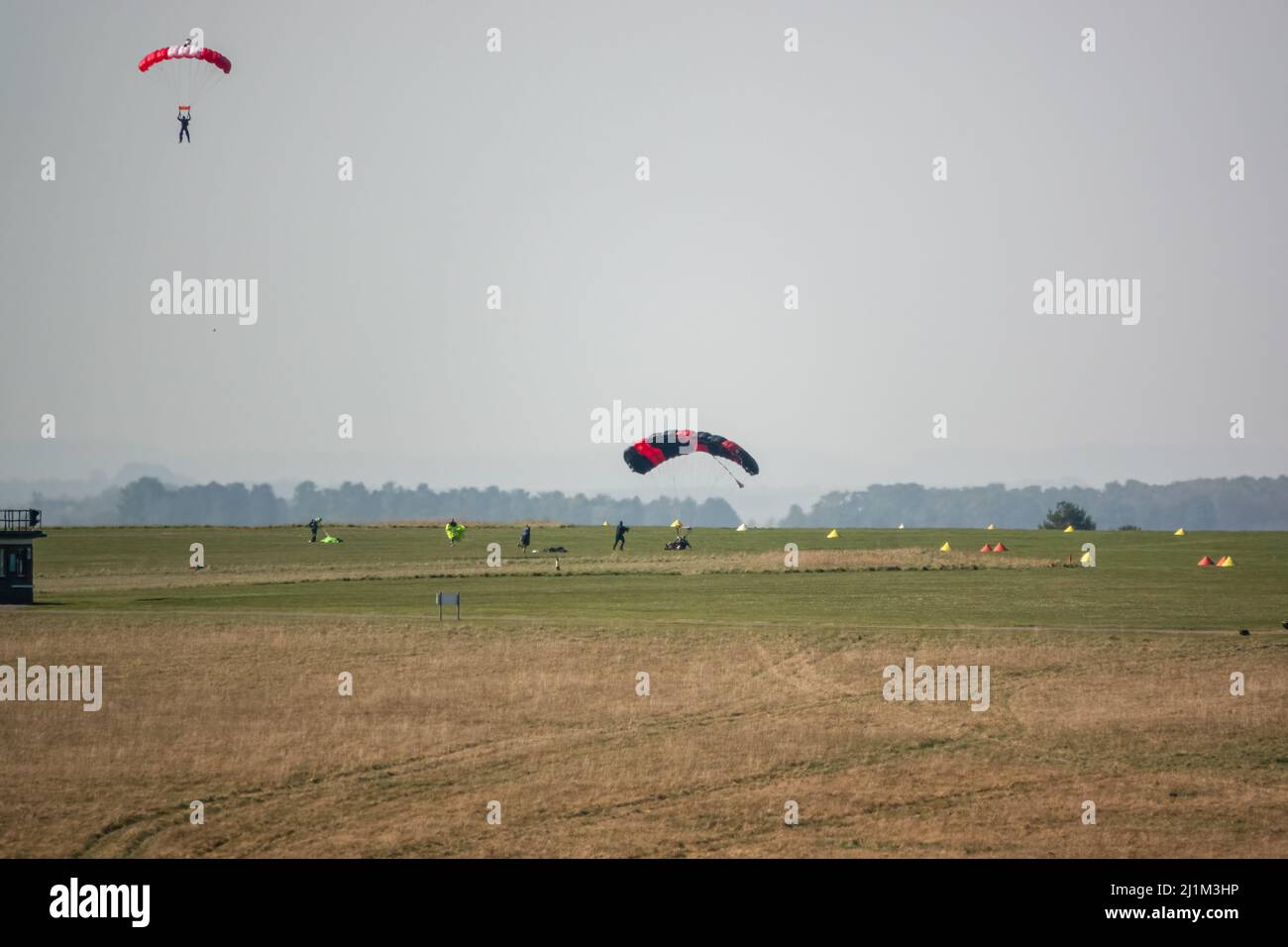 Saut en parachute arrivant sur un terrain d'aviation en herbe, ciel bleu Banque D'Images