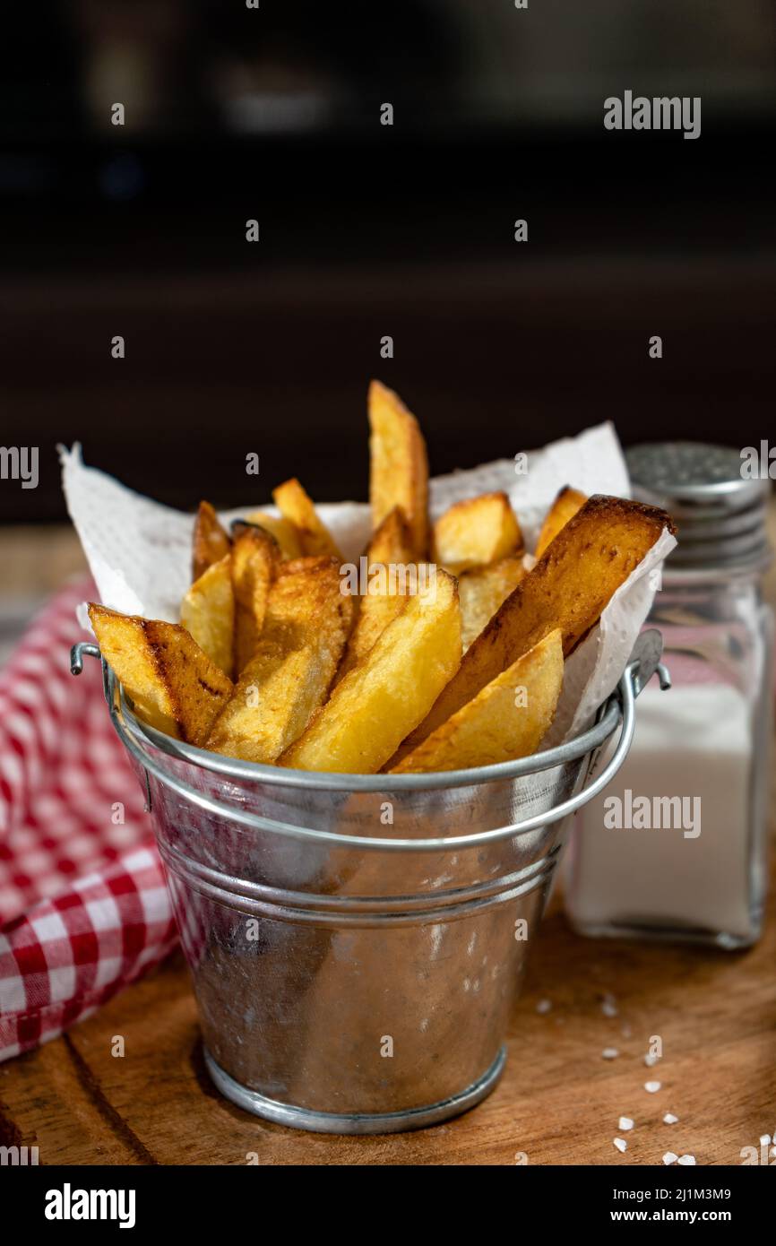 Frites dans une casserole en métal avec aïoli et ketchup sur une planche de bois. Orientation verticale, espace de copie. Banque D'Images