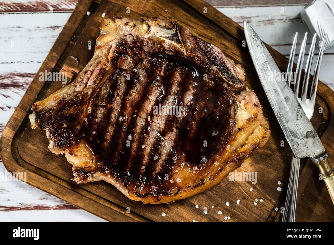 Incroyable t-bone cuit sur le gril ou barbecue sur un panneau en bois avec des couverts sur le côté. Vue de dessus. Banque D'Images