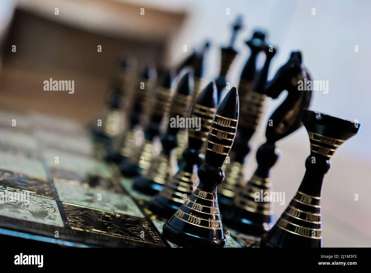 Échiquier avec pièces d'échecs alignées avec des couleurs noir et or. Banque D'Images