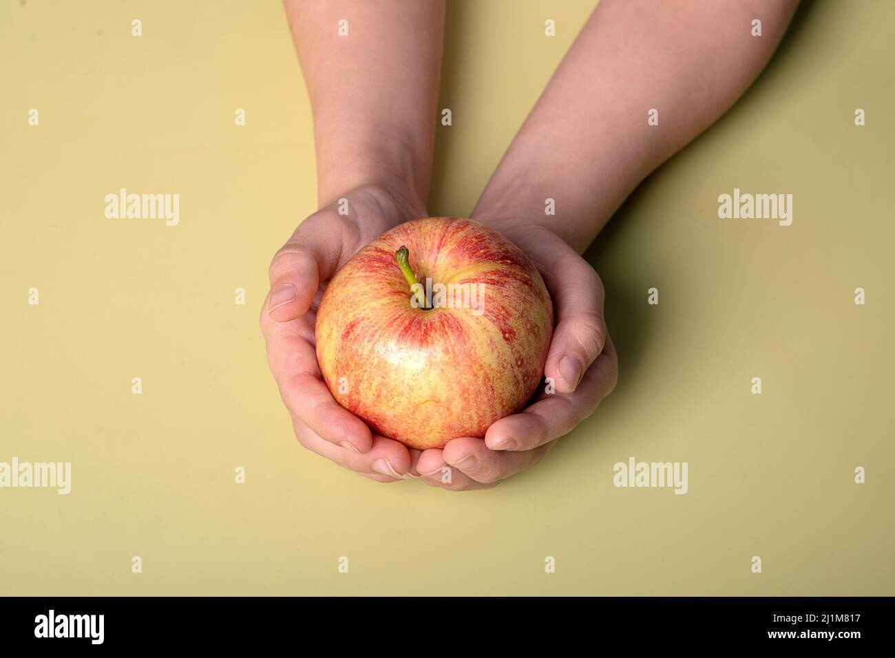 des pommes juteuses, fraîches et rouges dans les mains d'un enfant Banque D'Images