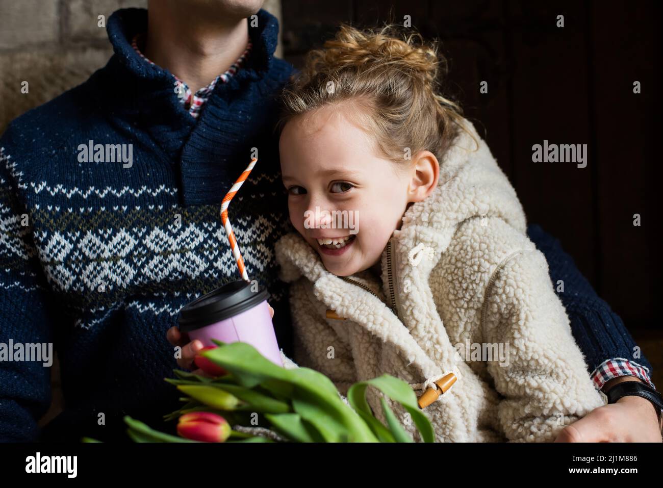 une fille qui câlin son papa tout en buvant du chocolat chaud Banque D'Images
