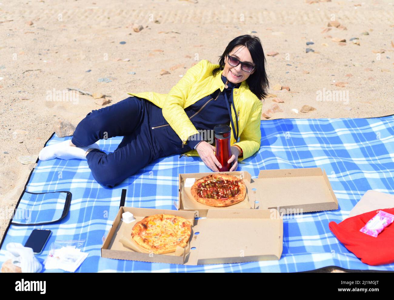 Femme russe de 45 ans qui va manger de la pizza tout en étant assise sur la plage Banque D'Images