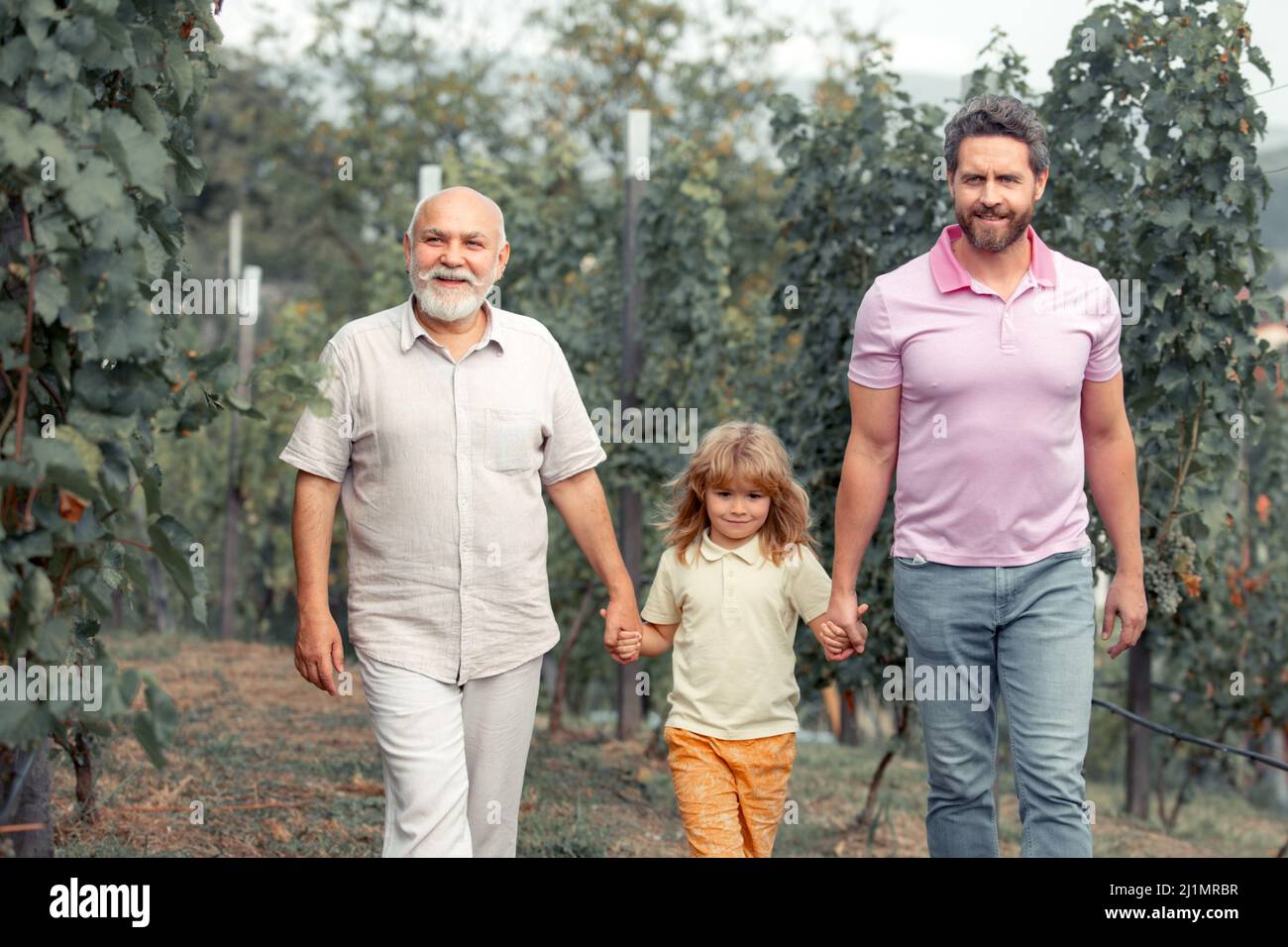 Famille de génération masculine avec trois générations différentes âges. Grand-père père père et fils marchant jardin de source. Banque D'Images