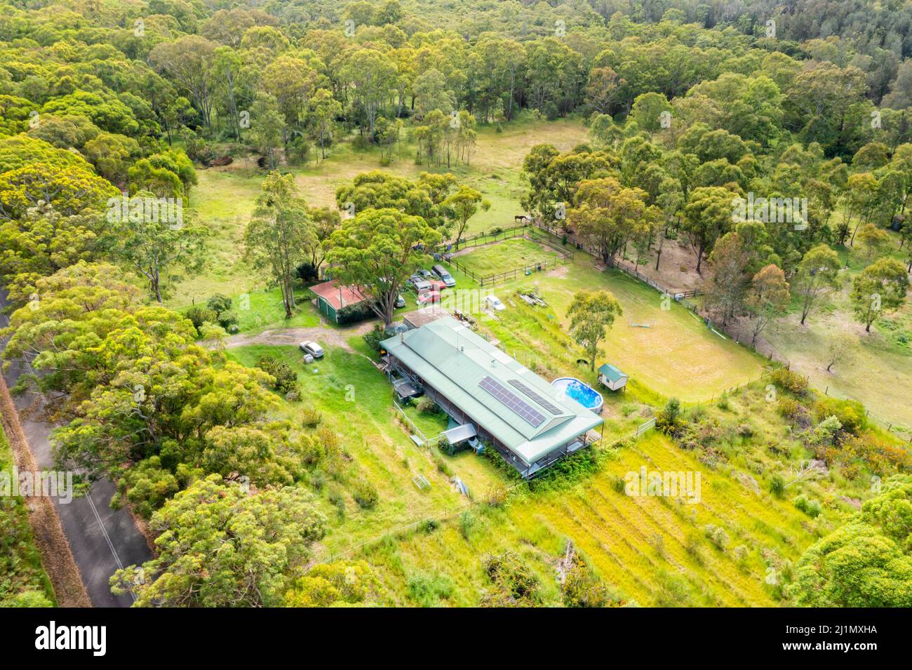 Ferme agricole verte isolée et maison dans des bois de gum-arbres sur la côte centrale australienne, paysage aérien. Banque D'Images