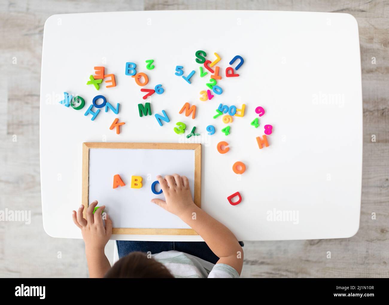 Classes de langue étrangère. Vue de dessus de Kid Making ABC note avec des lettres anglaises colorées, vue de dessus, espace vide Banque D'Images