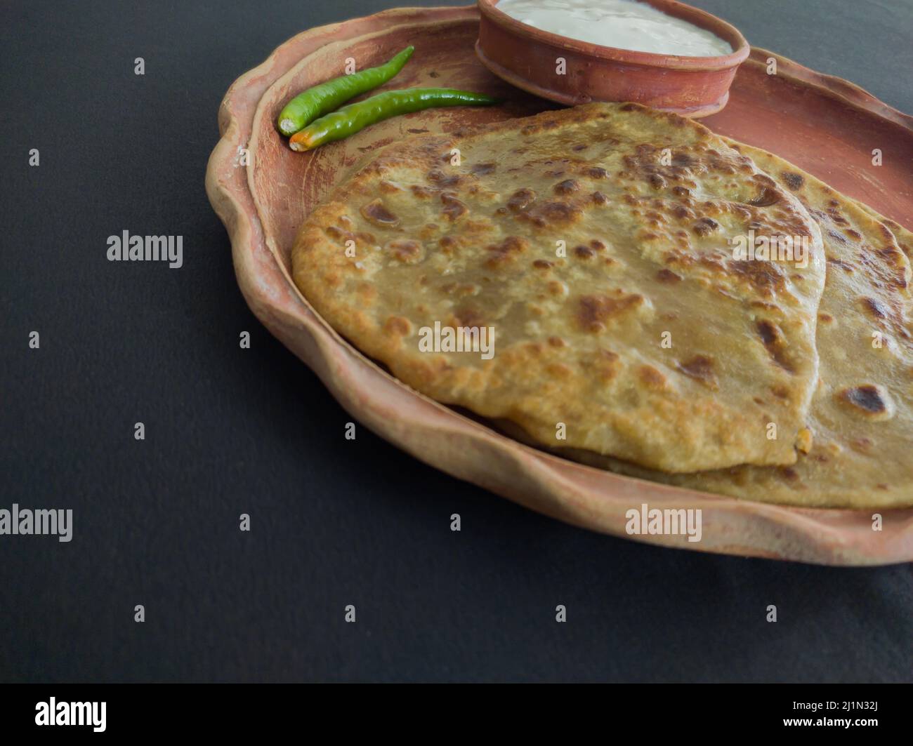 aloo paratha avec caillé servi sur plaque. Cuisine traditionnelle du nord de l'inde. Prise de vue sur fond noir. Banque D'Images