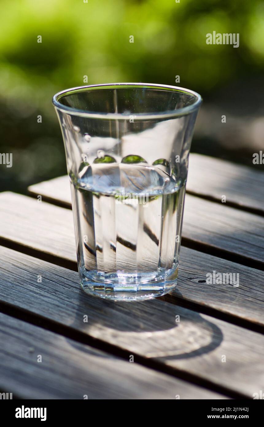 Boire du verre avec de l'eau douce sur une table en bois à l'extérieur en été. Banque D'Images