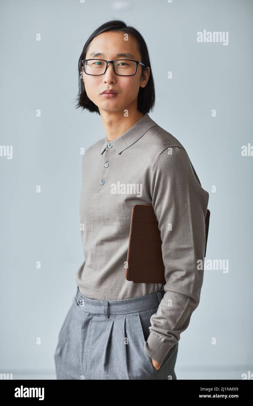 Portrait vertical minimal de jeunes hommes d'affaires asiatiques vêtus de gris sur fond bleu clair Banque D'Images