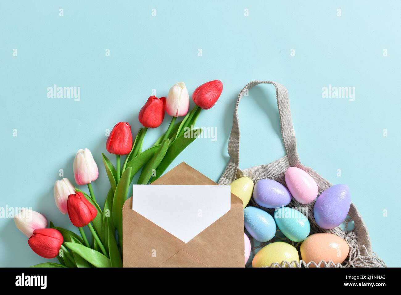 Un beau bouquet de tulipes avec un sac à cordes contenant des œufs peints. Banque D'Images