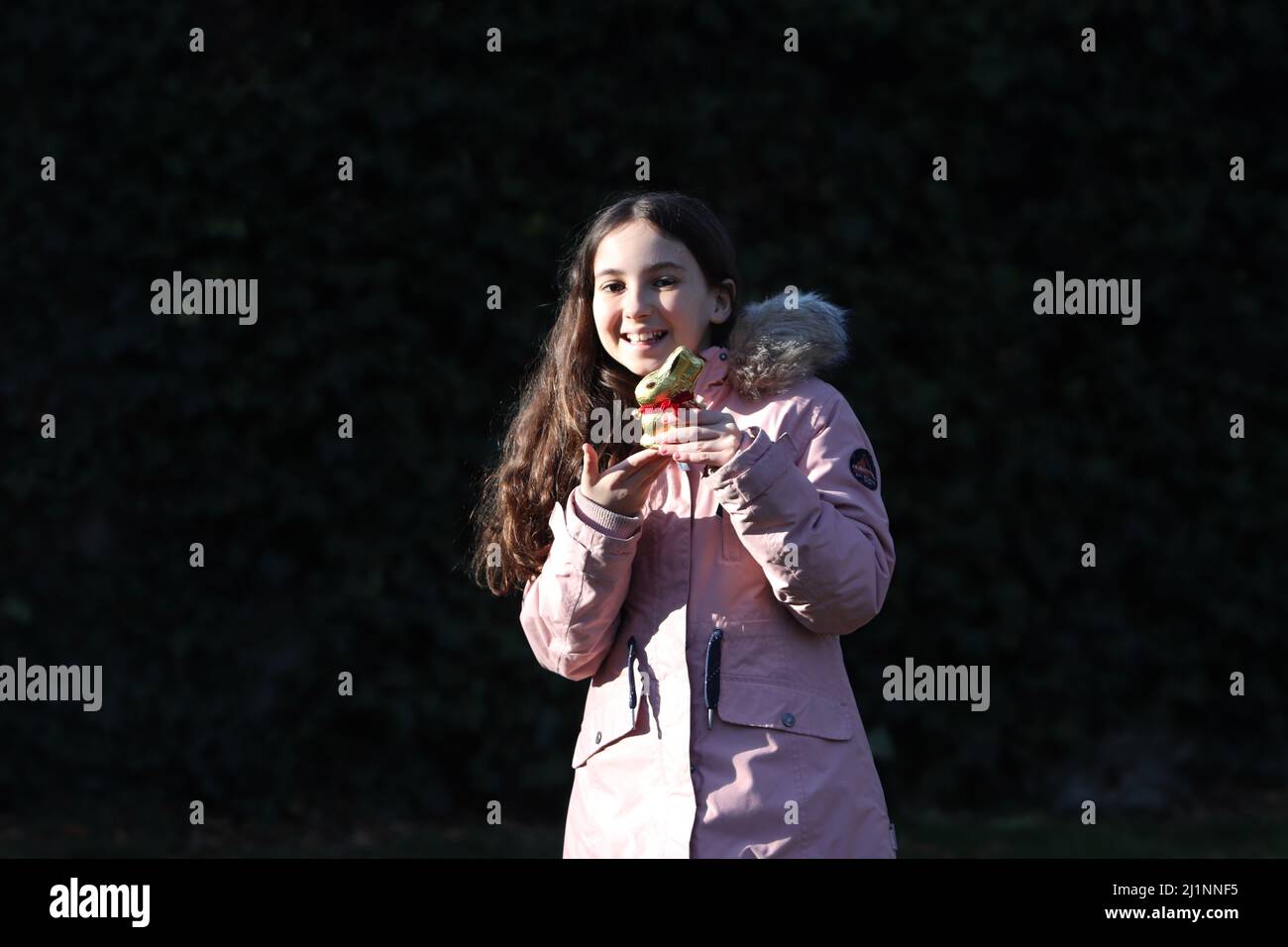 Genève, Suisse - 03 07 2022 bonne jeune fille avec lapin de pâques doré sur les mains. Une fille fête le cadeau de Pâques en plein air dans un parc ou une forêt.très petit enfant Banque D'Images