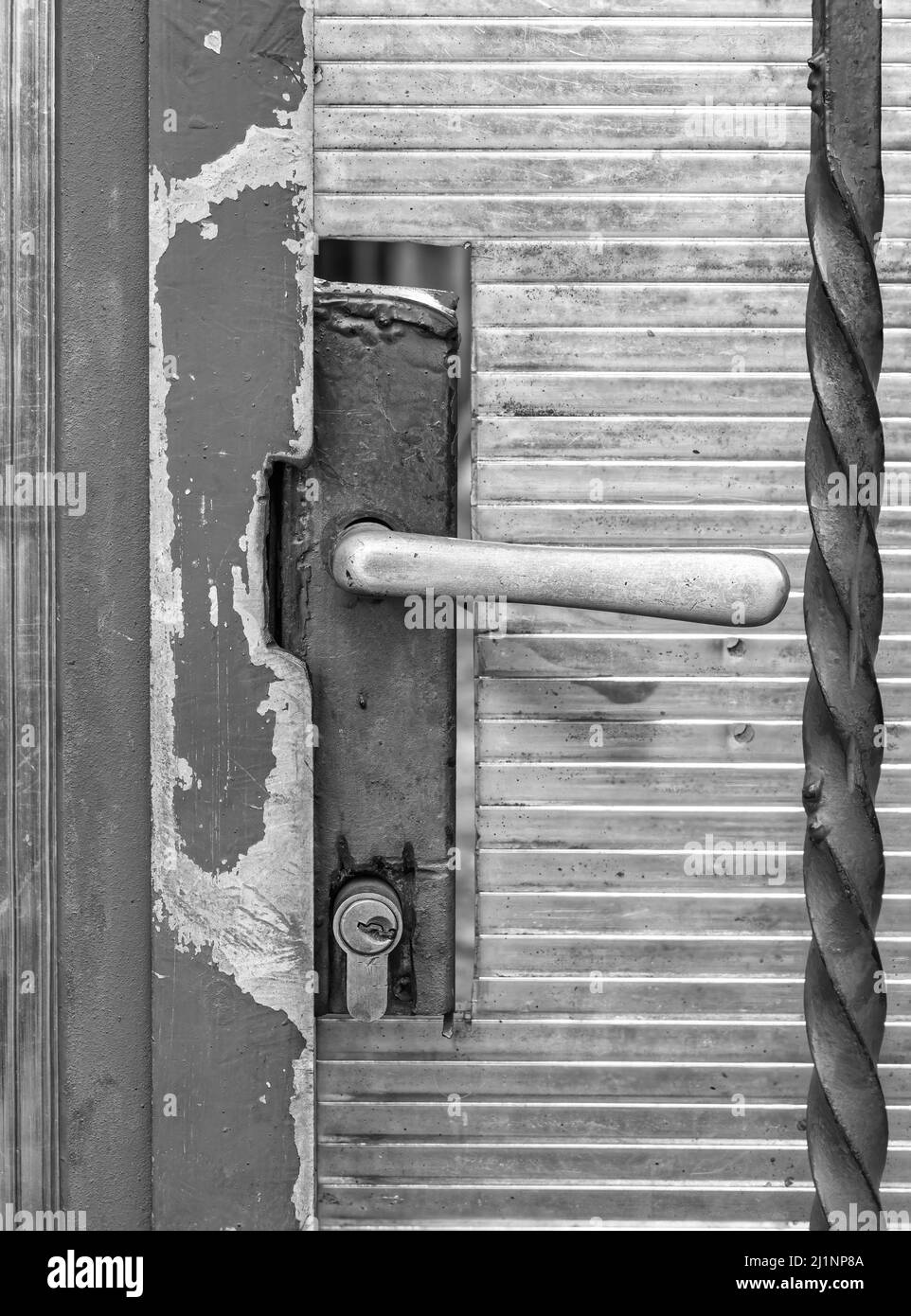 Image monochrome avec un vieux bouton de porte sur une porte en métal usée. Banque D'Images