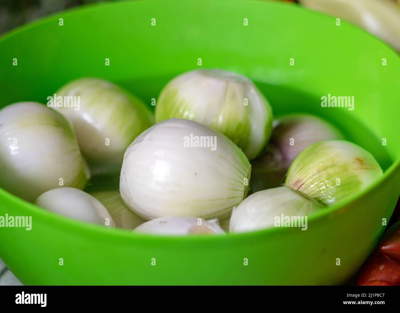 photo en couleur avec oignons pelés dans un bol vert, oignons préparés pour la conservation à la maison, temps de récolte d'automne Banque D'Images