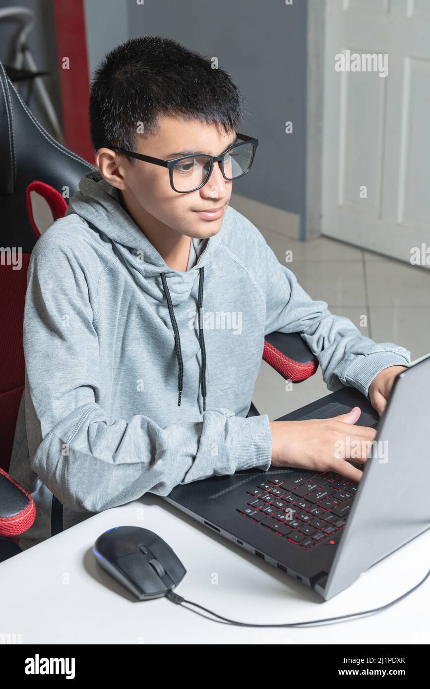 Adolescent garçon à la maison école étudier chambre bureau PC ordinateur lunettes assis regardant les devoirs Banque D'Images