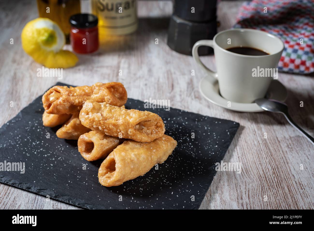 Pestiños à côté d'une tasse de café, avec certains des ingrédients utilisés dans sa préparation. Banque D'Images