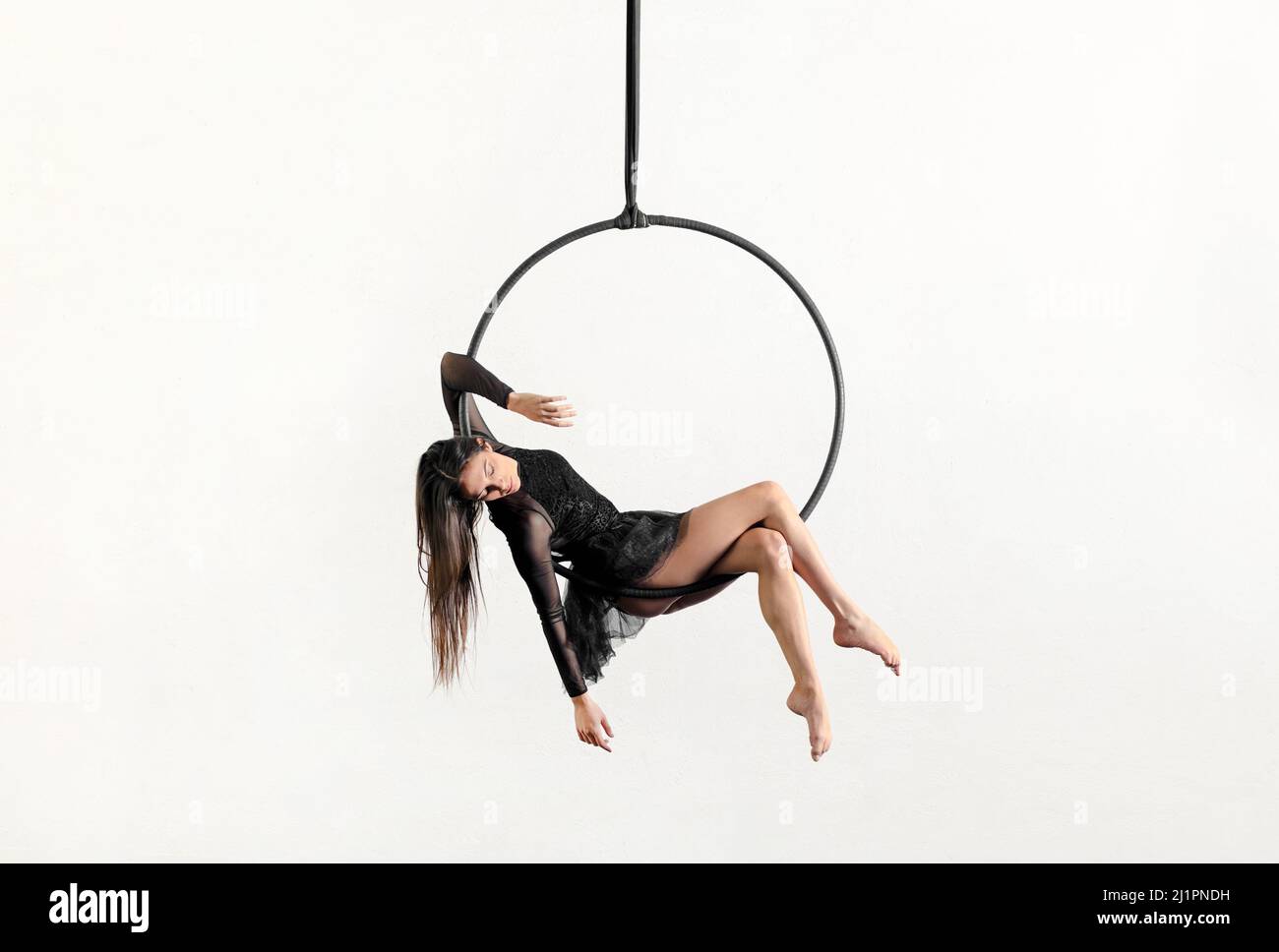 Corps complet de la femme acrobatique aerialiste montrant le berceau pose sur un panier suspendu au-dessus du sol sur fond blanc Banque D'Images