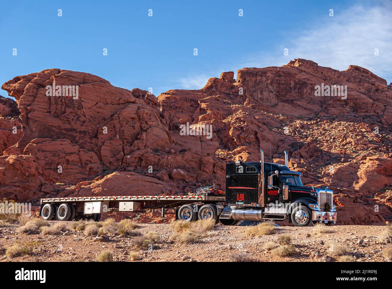 Overton, Nevada, États-Unis - 11 décembre 2010 : Vallée de feu. Gros plan sur une remorque à plateau et des tours en camion rouge-noir Kel-West en face de la montagne de Red Rock Banque D'Images