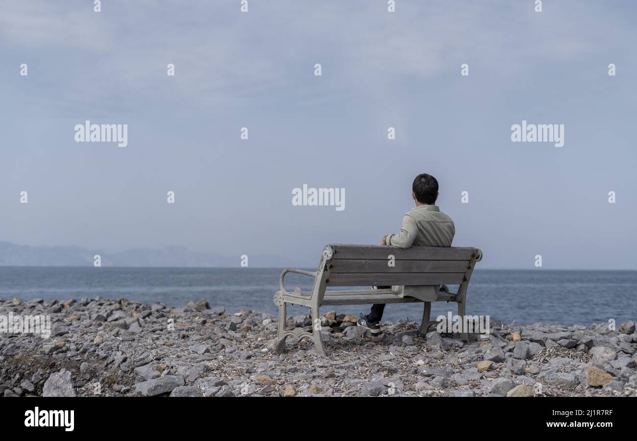 Homme solitaire déprimé assis sur une banque au bord de la mer. Banque D'Images