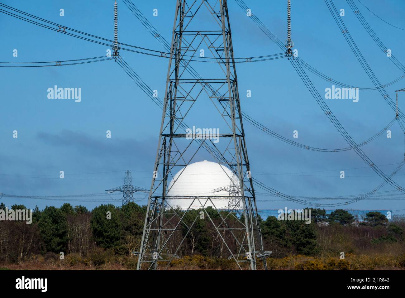 Le dôme blanc de la centrale nucléaire de Sizewell vu à travers le cadre métallique d'un pylône Banque D'Images
