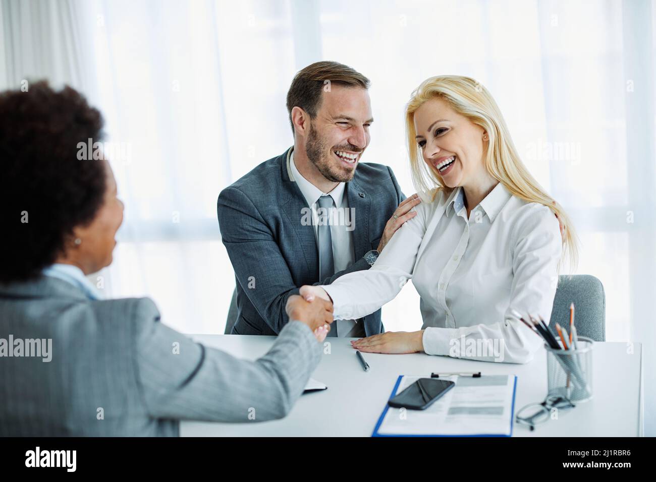 jeune couple qui tremble les mains traiter contrat immobilier investissement bureau d'affaires agent d'accord Banque D'Images