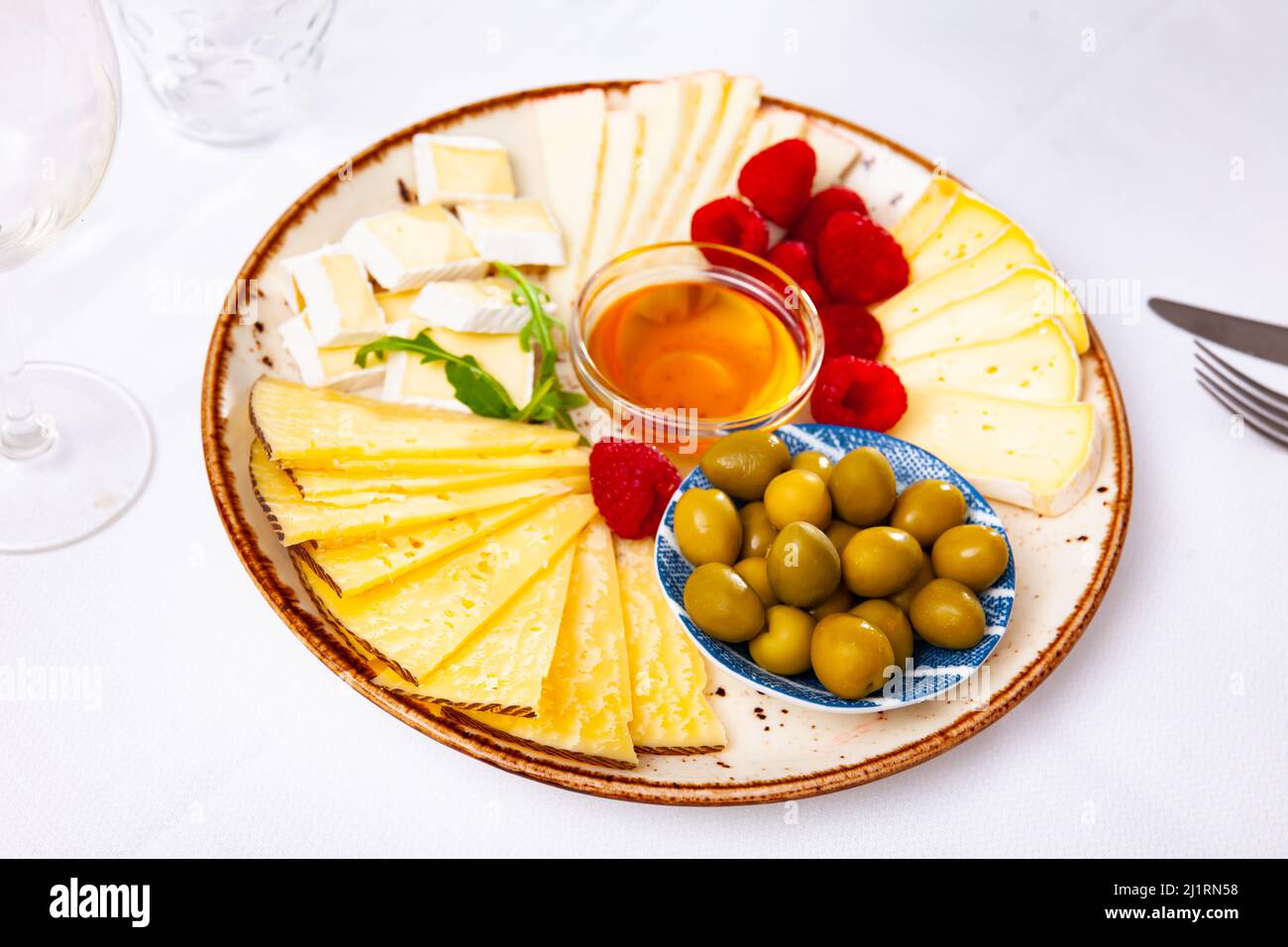 Différents types de fromage, miel, framboises et olives sur bois Banque D'Images