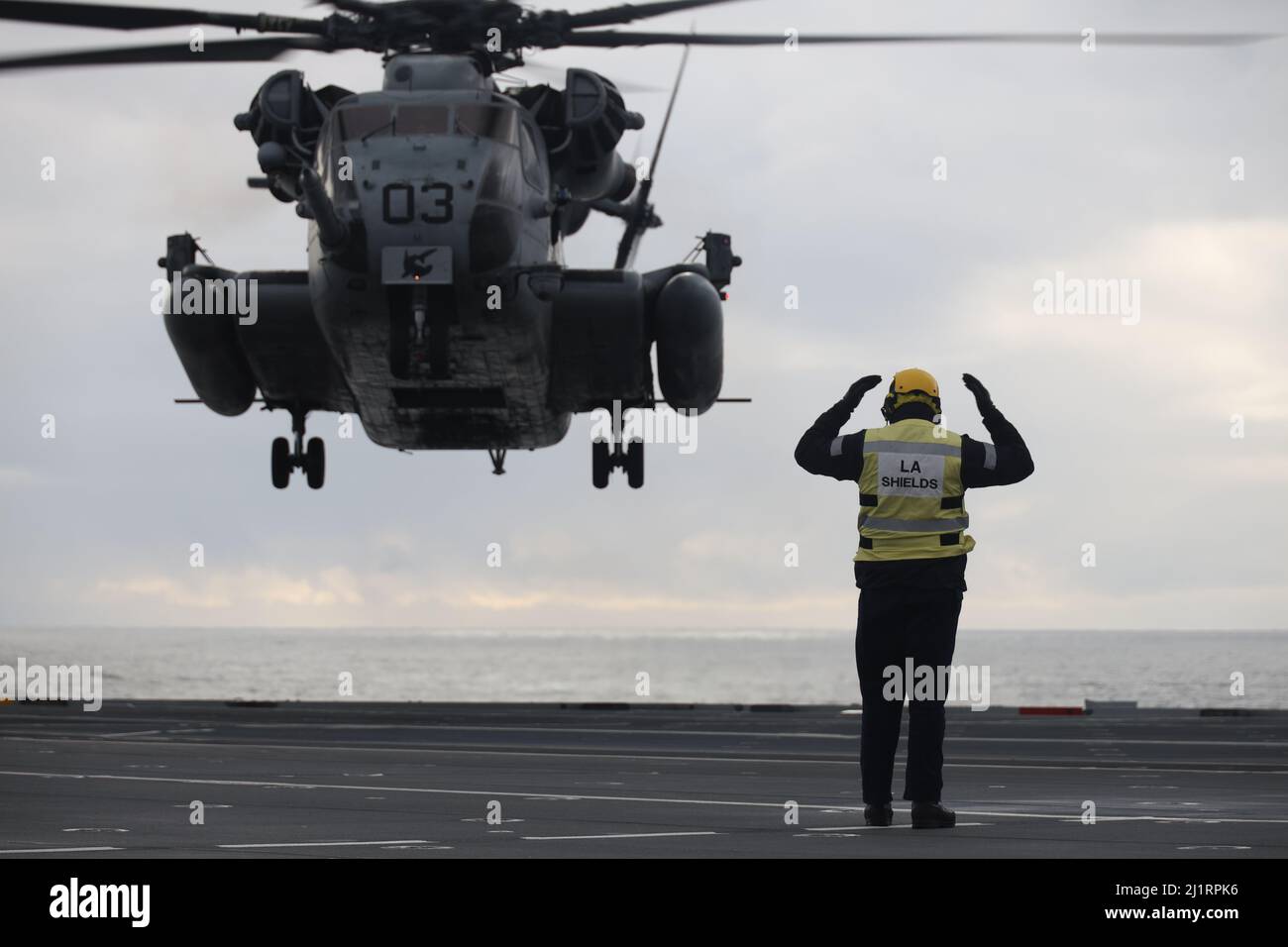 Un marin de la Royal Navy britannique signale un atterrissage à un Super Stallion CH-53E pendant l'exercice Cold Response 2022, Mer norvégienne, 24 mars 2022. Le CH-53E Super Stallion est affecté au Marine Heavy Helicopter Squadron (HMH) 366, Marine Aircraft Group 29, 2D Marine Aircraft Wing. L'exercice Cold Response '22 est un exercice biennal de préparation nationale et de défense norvégien qui a lieu dans toute la Norvège, avec la participation de chacun de ses services militaires, ainsi que de 26 autres nations alliées de l'OTAN et partenaires régionaux. (É.-U. Photo du corps marin par Sgt. Jonathon Wiederhold) Banque D'Images