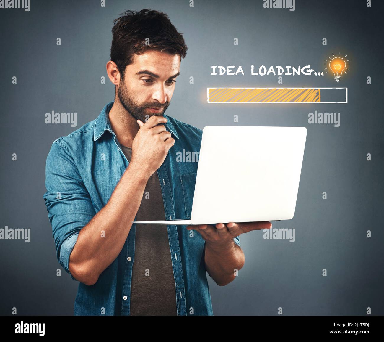 Son idée est en train de se charger. Photo studio d'un jeune homme charmant qui a l'air attentif tout en travaillant sur son ordinateur portable à côté d'une illustration d'une barre de chargement Banque D'Images