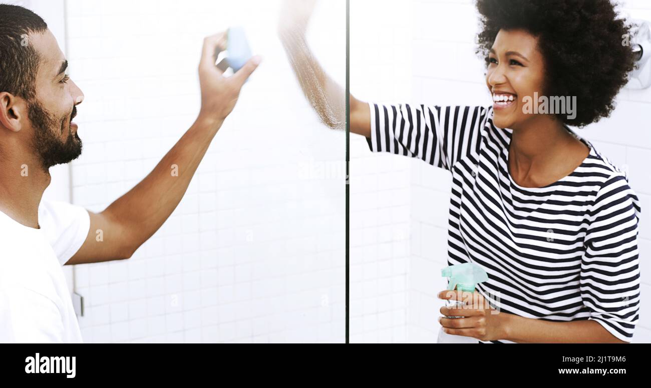 Plus les mains sont nombreuses, moins le travail est important. Photo d'un jeune couple gai lavant une porte de douche en verre avec une éponge dans la salle de bains à la maison. Banque D'Images