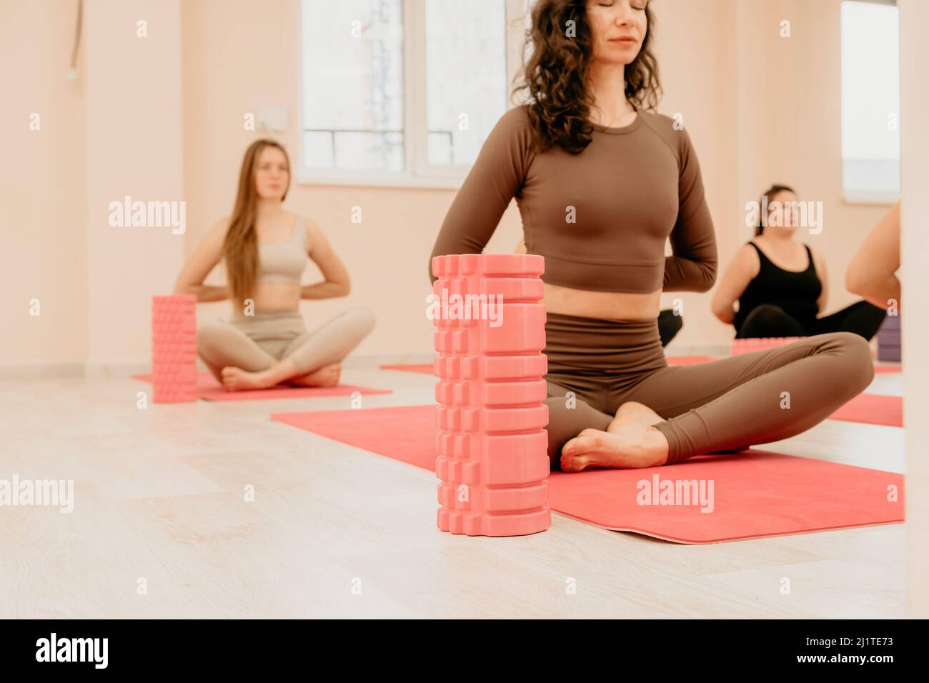 Femmes d'âge moyen bien regardant, effectuant des exercices de structure d'affichage sur le plancher à l'aide d'un rouleau en mousse de massage - outil pour soulager la tension dans le dos et soulager Banque D'Images