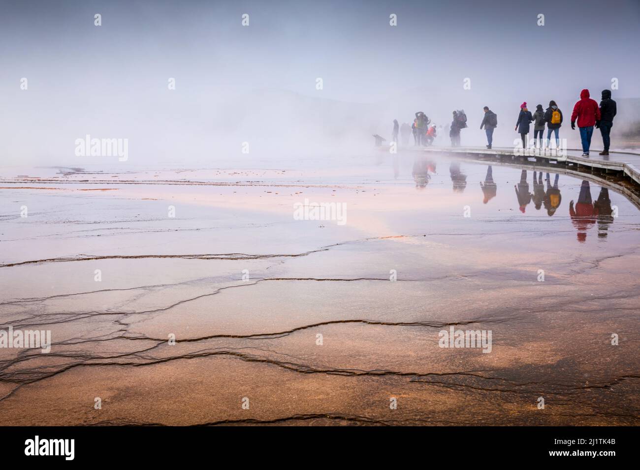 Wyoming, Etats-Unis - 1 octobre 2019 : scène brumeuse de touristes marchant sur une promenade en bois à l'intérieur de la surface humide orange de Grand Prismatic Spring, le plus famo Banque D'Images