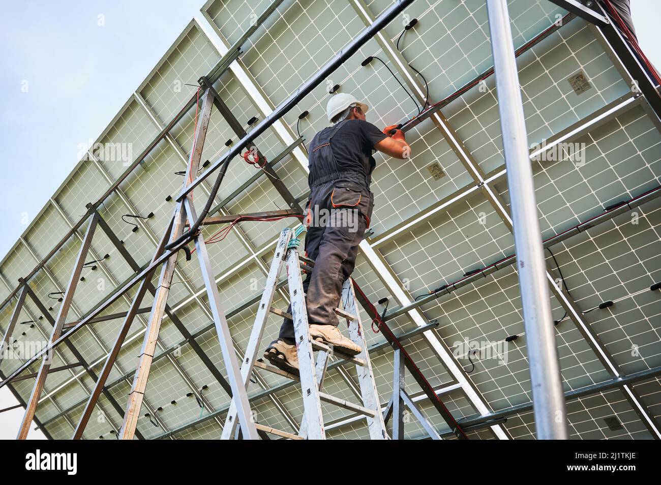 Un électricien mâle câblera les panneaux solaires ensemble. Homme installant un système de panneaux solaires photovoltaïques à l'extérieur. Concept de sources d'énergie renouvelables. Banque D'Images