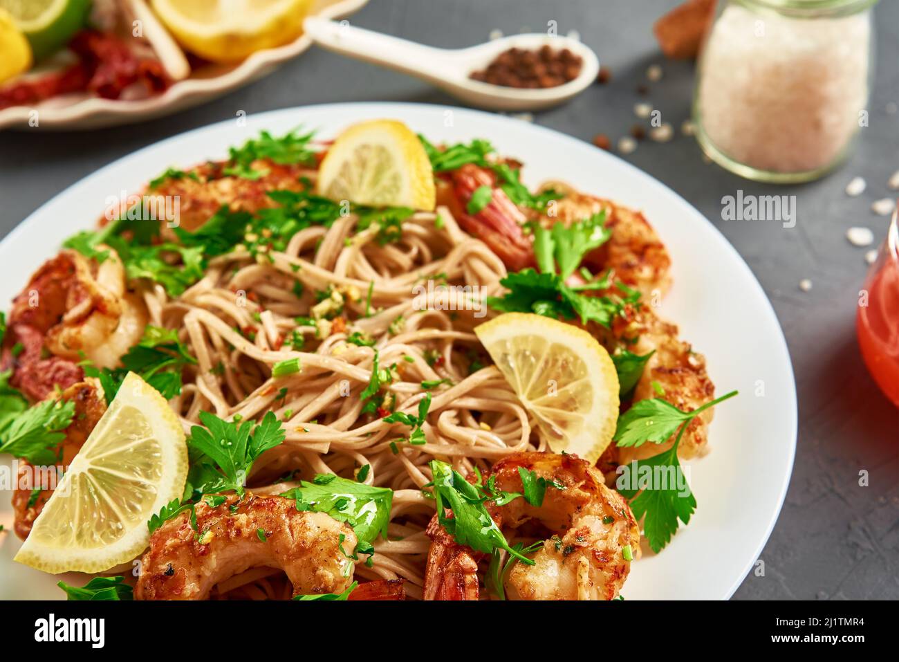 Sauté de nouilles aux crevettes, citron et persil frais sur une assiette blanche, soba aux crevettes, cuisine asiatique, vue de dessus Banque D'Images