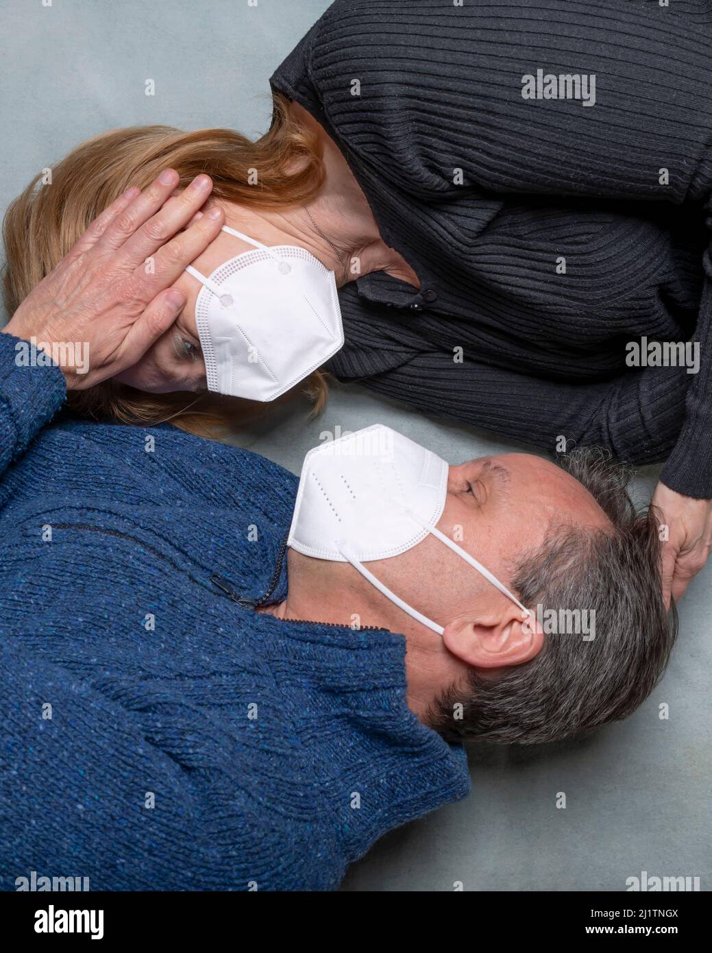 Vue de dessus d'une femme et d'un homme allongé sur le sol croisés se caressant les uns les autres, portant un masque facial Banque D'Images