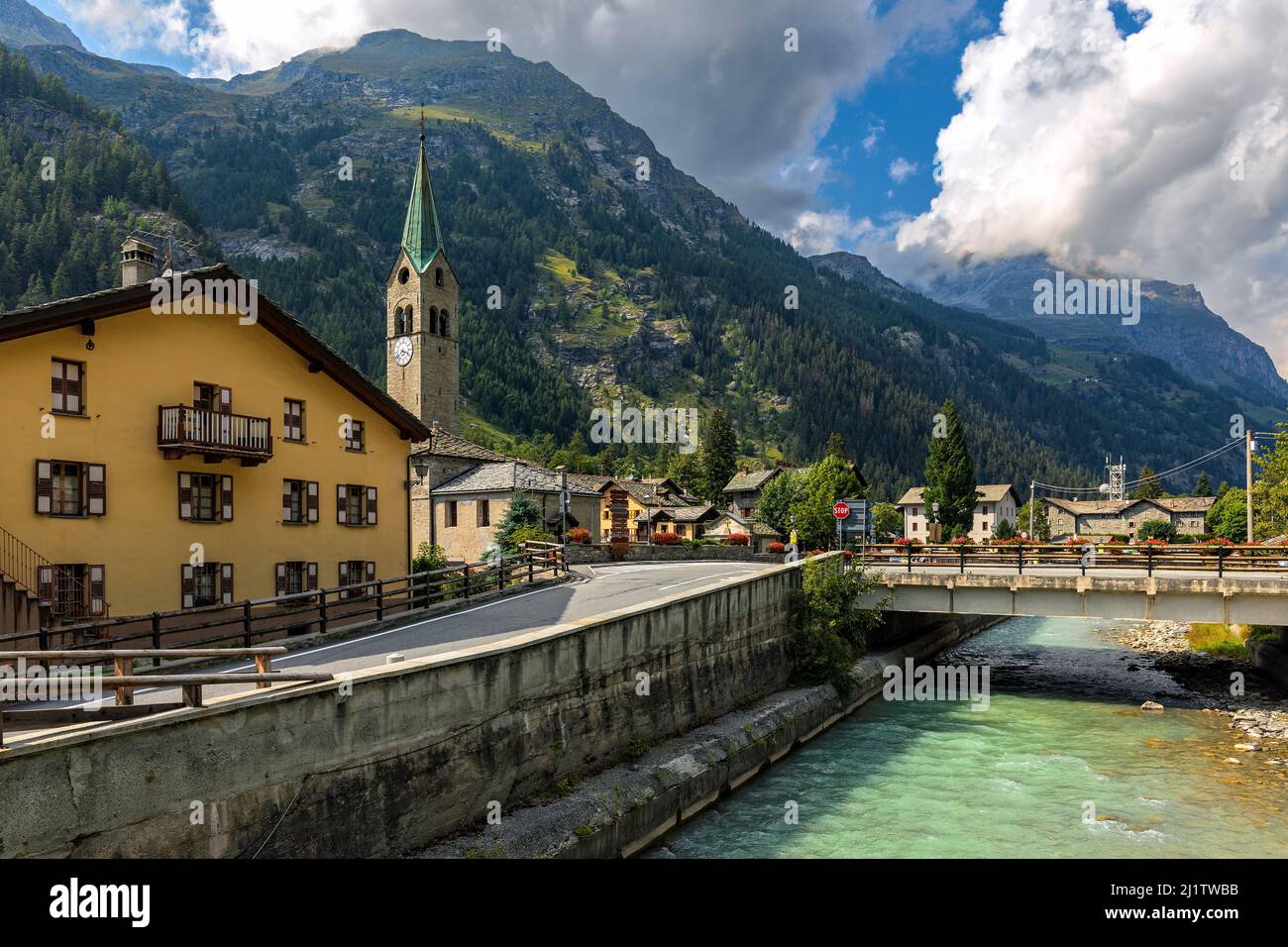 Pont sur la rivière de montagne le long des maisons et de la vieille église en arrière-plan dans la petite ville de Gressoney-Saint-Jean dans la vallée d'Aoste, Italie. Banque D'Images