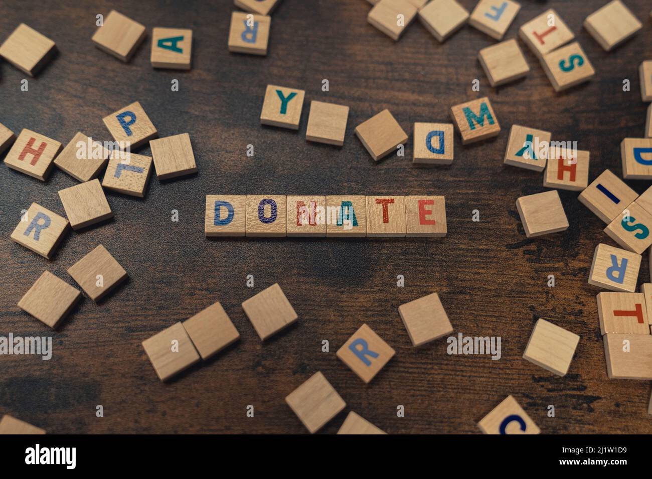 DONNER - un mot mis avec des lettres de l'alphabet sur le concept de table de charité en bois brun. Photo de haute qualité Banque D'Images