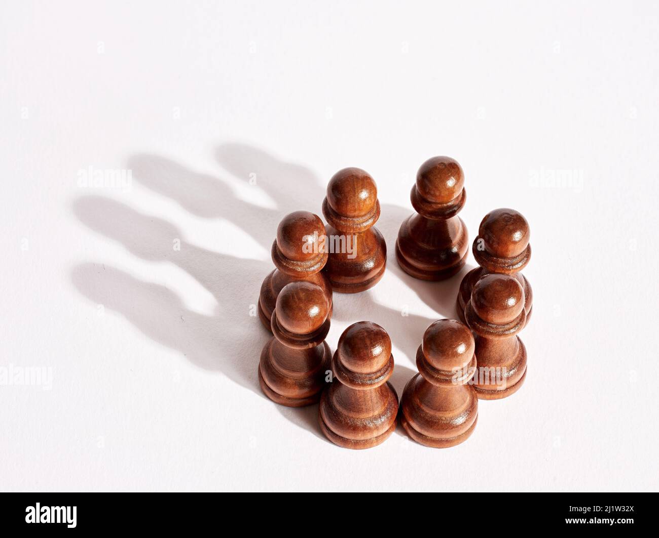 Pions d'échecs organisés ensemble et formant une ombre de couronne. Concept de leadership et de synergie pour le travail d'équipe d'entreprise. Banque D'Images
