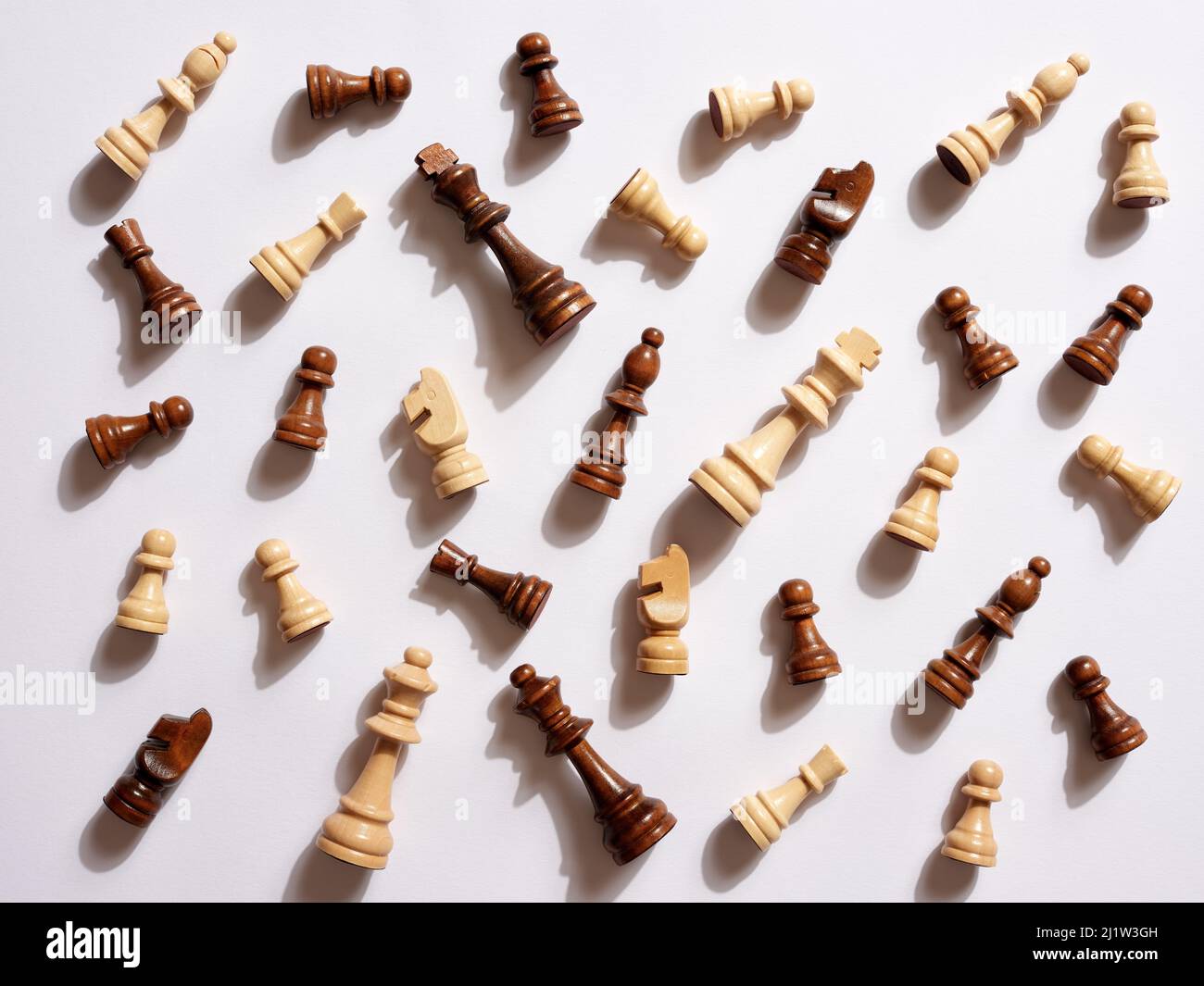 Vue de dessus des pièces d'échecs en bois blanc et brun tombés sur fond blanc. Banque D'Images