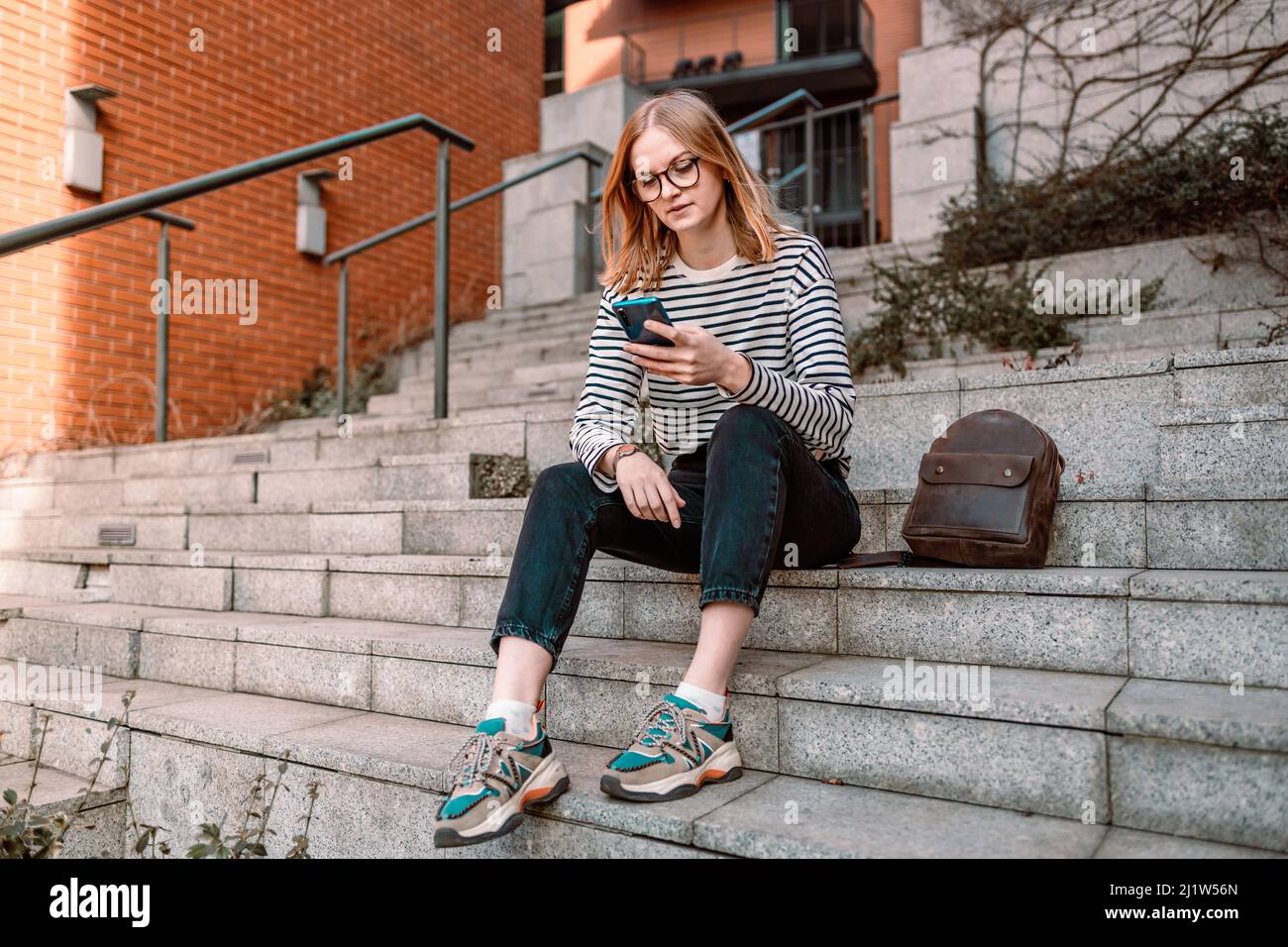 Bonne fille de 20s s'amuser en utilisant le téléphone mobile en plein air dans la ville Banque D'Images