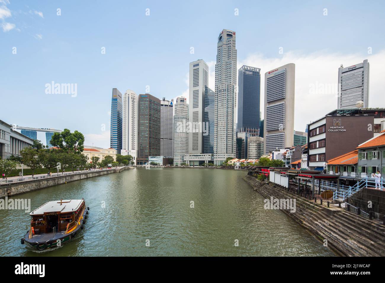 Plusieurs gratte-ciels se sont concentrés en arrière-plan, un bum-boat se déplaçant le long de la rivière propre de Singapour. 2022. Banque D'Images