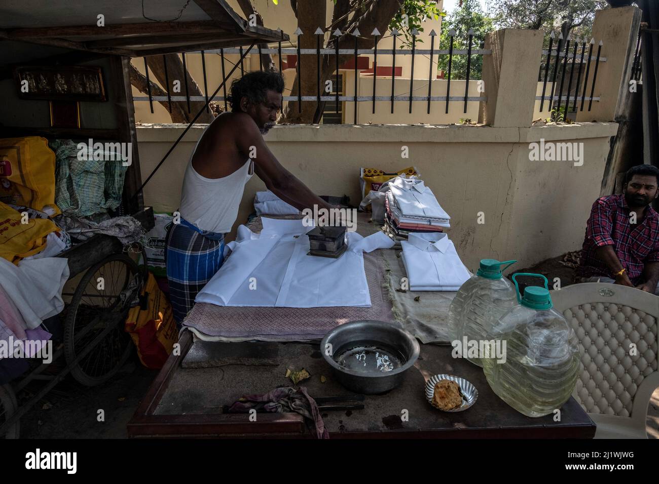 Presser des vêtements de pressage avec un fer à charbon sur le marché à Tiruvannamalai, Tamil Nadu, Inde Banque D'Images