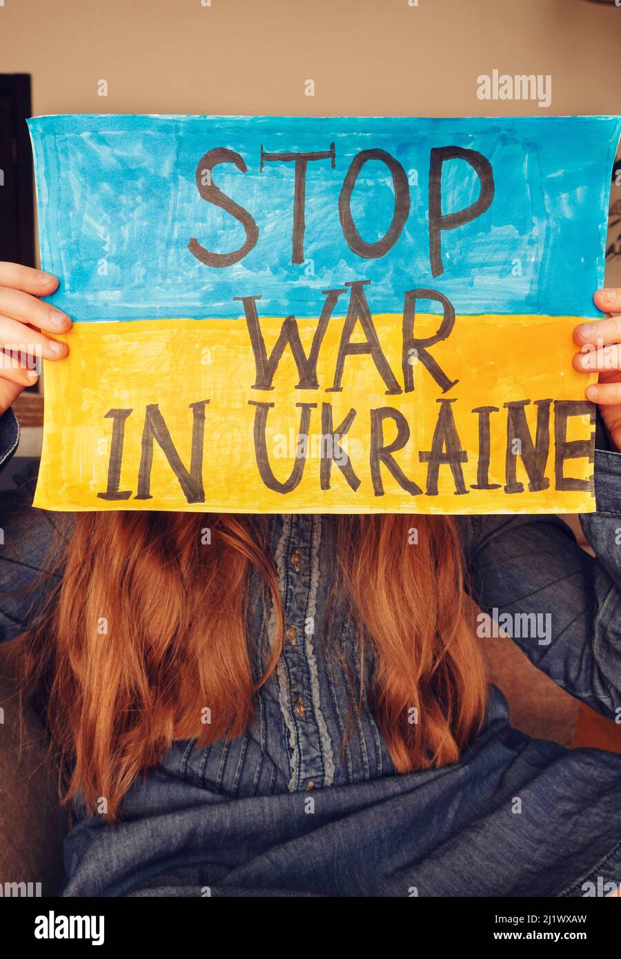 Petite fille ukrainienne tient une image avec le drapeau de l'Ukraine et le texte ARRÊTER LA GUERRE EN UKRAINE. Russe envahissant l'Ukraine. Banque D'Images