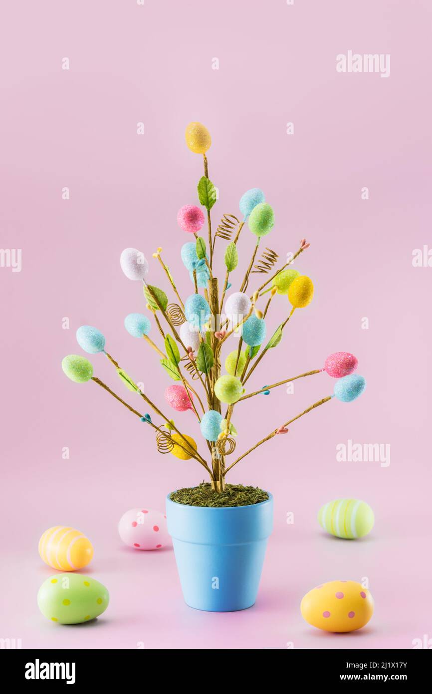 Décoration de sapin de Pâques dans un pot bleu avec œufs colorés sur fond rose clair. Décor de fête minimaliste. Maquette moderne de carte de Pâques tendance. Banque D'Images Décoration de sapin de Pâques dans un pot bleu avec œufs colorés sur fond rose clair. Décor de fête minimaliste. Maquette moderne de carte de Pâques tendance. Banque D'Images