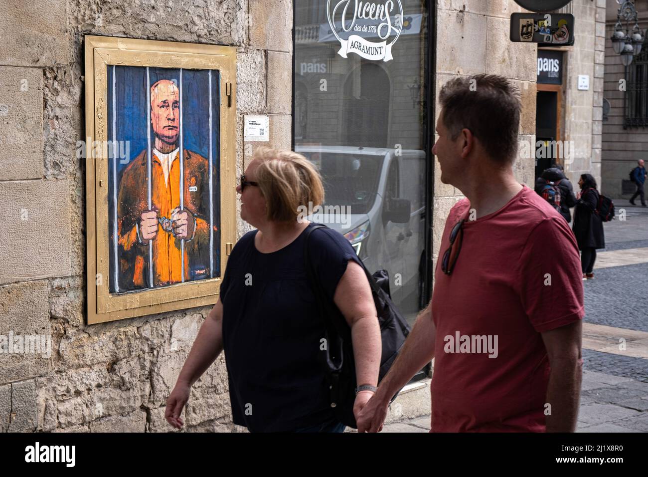 Barcelone, Espagne. 28th mars 2022. Les gens regardent tout en marchant devant un portrait de Vladimir Poutine derrière les barreaux. Vladimir Poutine derrière les barreaux est représenté dans le nouveau collage graphique public de la Plaza de Sant Jaume par l'artiste italien TvBoy basé à Barcelone. (Photo par Paco Freire/SOPA Images/Sipa USA) crédit: SIPA USA/Alay Live News Banque D'Images